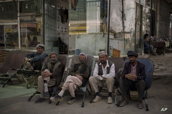 Workers sit on their wheelbarrows as they wait to be hired on the side of the road in Kabul, Afghanistan, Friday, Oct. 8, 2021…