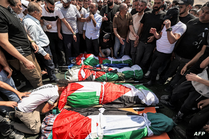 EDITORS NOTE: Graphic content / Mourners gather by the bodies of four men who were killed in an Israeli military operation,…
