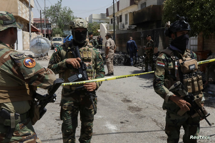 Members of Iraqi security forces stand near the debris of an armed drone shot down by Iraq's air defences in Kirkuk