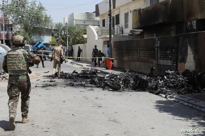 Members of Iraqi security forces stand near the debris of an armed drone shot down by Iraq's air defences in Kirkuk