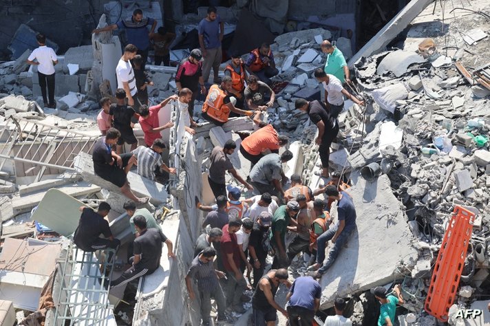 فلسطينيون يبحثون عن ناجين وسط أنقاض مبنى انهار بعد قصف إسرائيلي على مبنى مجاور له، في حي الشيخ رضوان بمدينة غزة في 23 سبتمبر 2024.
