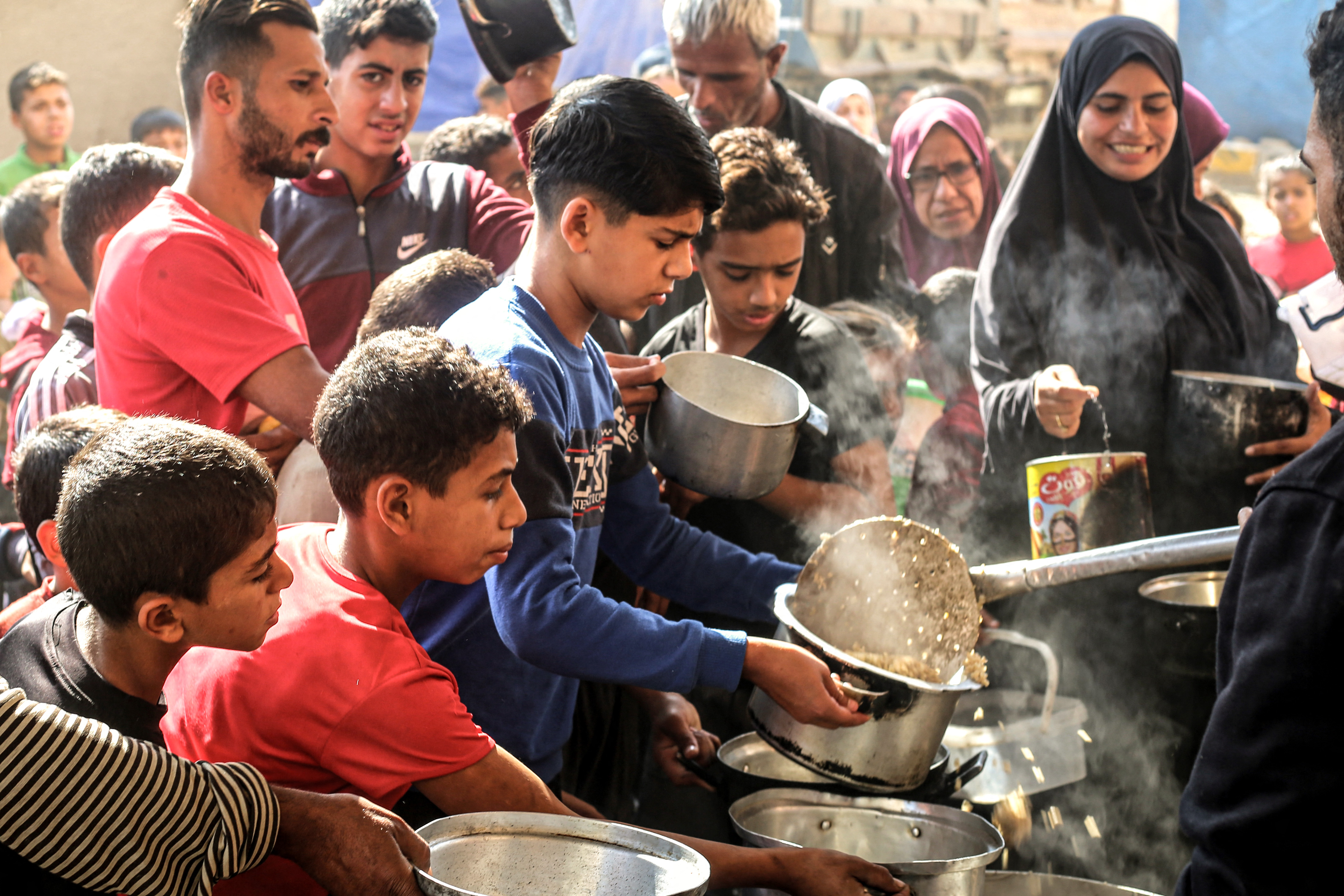 فلسطينيون يجمعون المساعدات الغذائية في مخيم البريج للاجئين وسط قطاع غزة