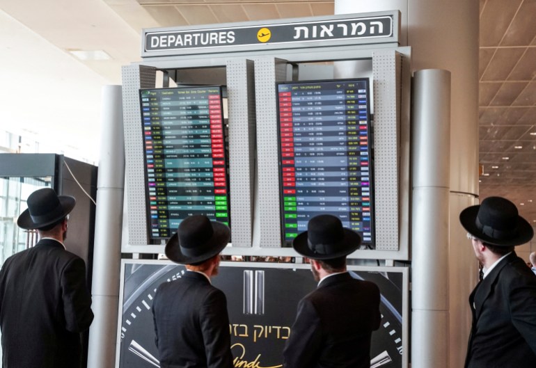 Travellers look at a monitor displaying delayed flights after take-offs were suspended as part of nationwide protests against the government's judicial overhaul plan, according to an airport spokesperson, at Ben Gurion International Airport in Lod, Israel March 27, 2023. REUTERS/Itai Ron