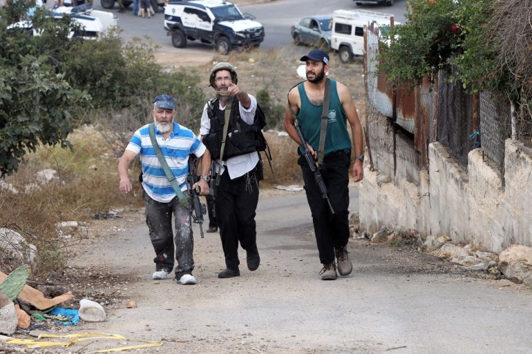 Armed Israeli settlers walk up a road at the site of a reported stabbing attack by a Palestinian on an Israeli settler, near the Israeli settlement of Kiryat Arba, near Hebron in the occupied West Bank on October 9, 2015. A fresh wave of stabbings shook Israel and the West Bank, including a suspected revenge attack by a Jewish suspect that wounded two Palestinians and two Arab Israelis. AFP PHOTO/HAZEM BADER (Photo by HAZEM BADER / AFP) (Photo by HAZEM BADER/AFP via Getty Images)