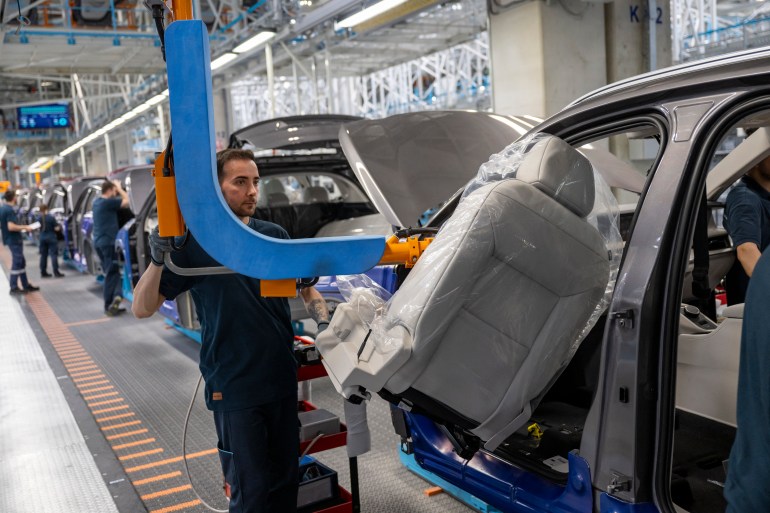 This photograph taken in Bursa on May 17, 2024 shows an employee working on a car assembly line at a factory of Togg at the Gemlik Togg Technology Campus. Thousands of vehicles are rolling off its campus on the Sea of Marmara, built in less than two years. Already renowned for its car manufacturing, Turkey is showing its teeth in the electric car market with its champion, Togg. (Photo by Yasin AKGUL / AFP)