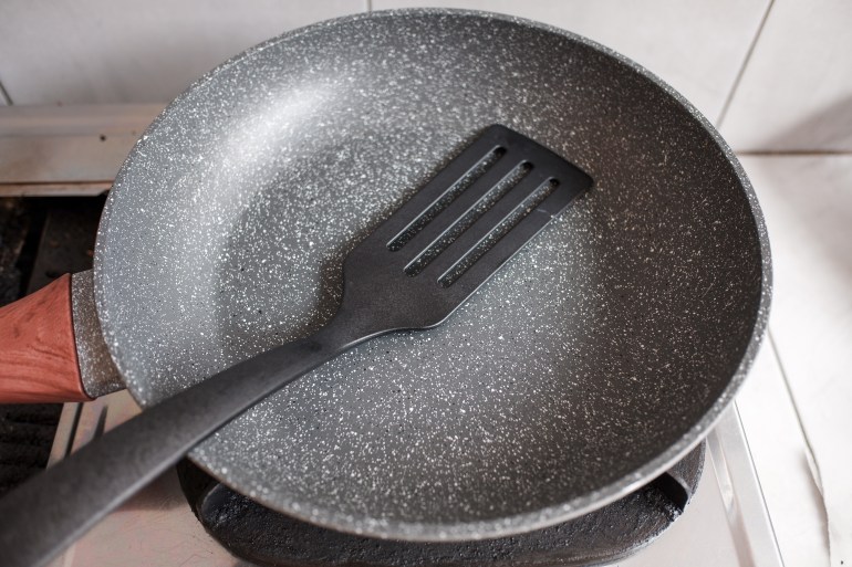 A non-stick Teflon frying pan with a plastic spatula on the stove, cooking utensil, in the kitchen.