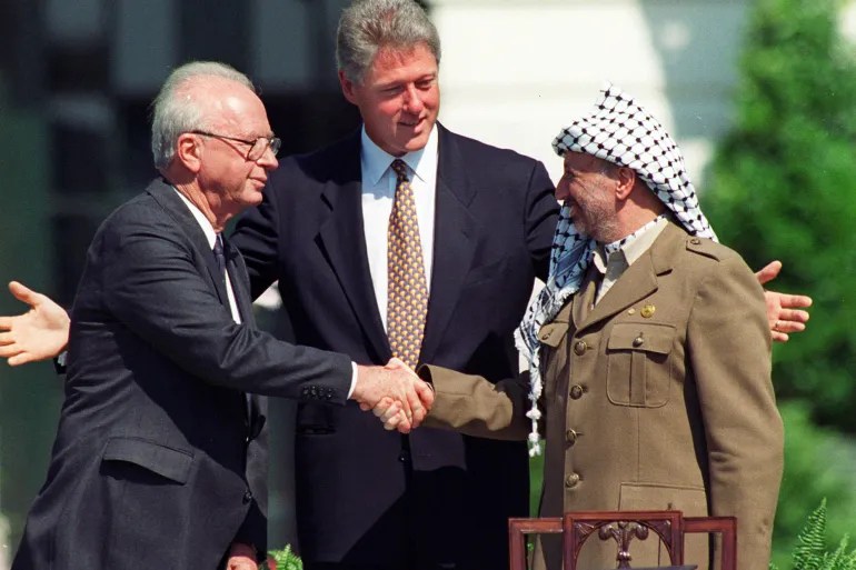 The famous White House lawn handshake between Israeli Prime Minister Yitzakh Rabin (left) and the head of the Palestine Liberation Organization Yasser Arafat (right), with US President Bill Clinton in the centre [File: Ron Edmonds/AP Photo]