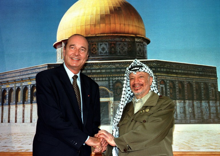 French President Jacques Chirac (L) and Palestinian President Yasser Arafat hold hands October 23 as they stand in front of a large photo mural of Jerusalem's Dome of the Rock at the close of their joint press conference.