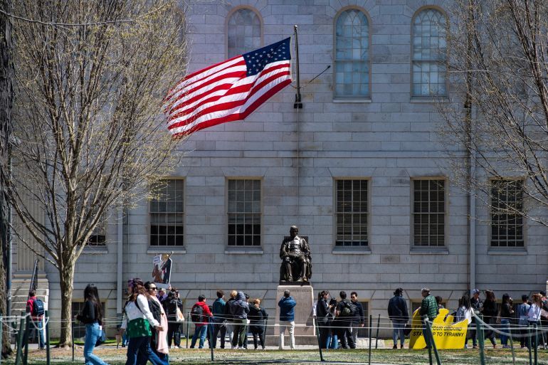 (FILES) Demonstrators with signs stand around the John Harvard Statue in Harvard Yard following a rally against President Donald Trump’s attacks on Harvard University at Harvard University in Cambridge, Massachusetts on April 17, 2025.