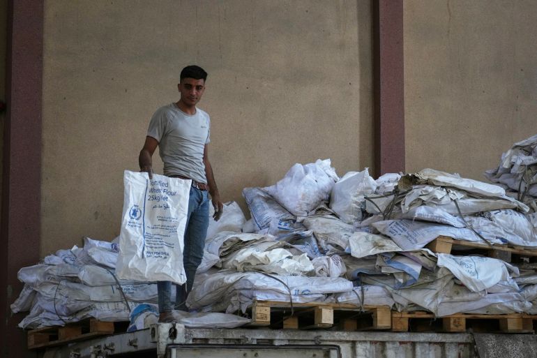 A Palestinian worker holds one of the empty sacks of flour at the World Food Program warehouse in the Nuseirat refugee camp, Gaza Strip, Saturday April 26, 2025. (AP Photo/Abdel Kareem Hana)