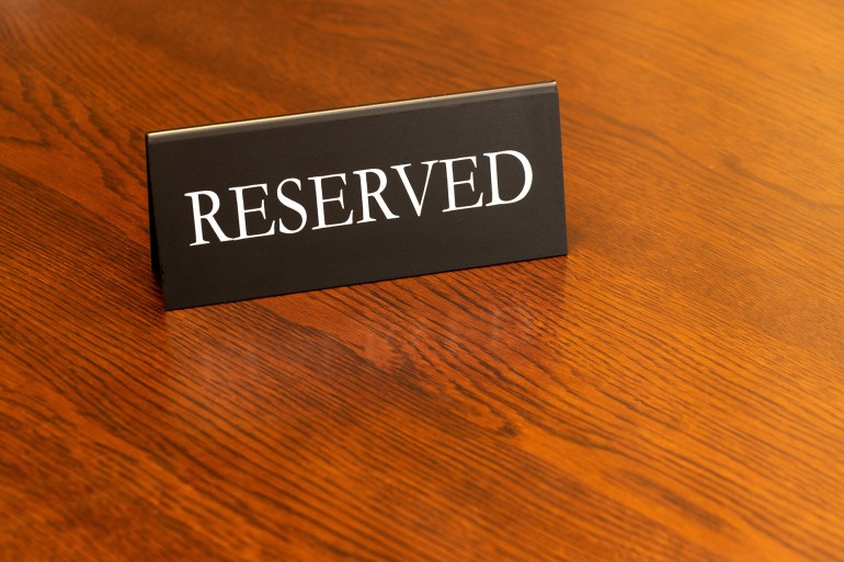 There is a sign on the wooden table indicating that this is a reserved seat.; Shutterstock ID 2437632219; purchase_order: aj; job: ; client: ; other: