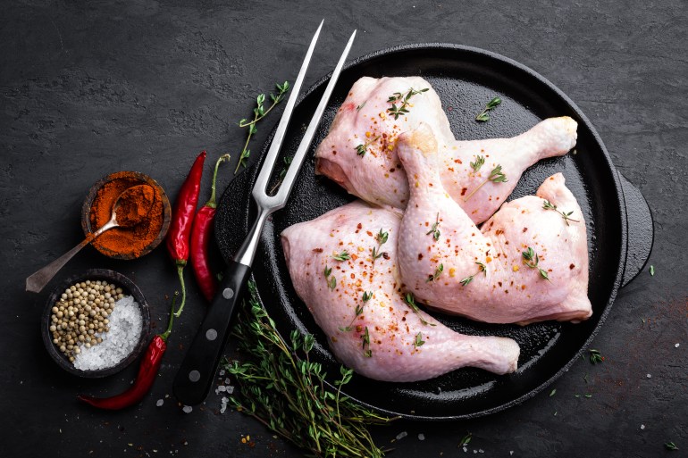 Raw chicken quarters, legs in a pan on a dark background. Top view.