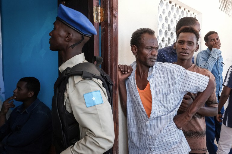 A Somali security officer monitors access as men queue for a voter registration exercise in Mogadishu on April 15, 2025. Somalia on April 15, 2025 launched voter registration in the capital Mogadishu for the first time in over 50 years, a step towards universal suffrage ahead of presidential elections scheduled for 2026 in the volatile East African nation. (Photo by Hassan Ali Elmi / AFP)