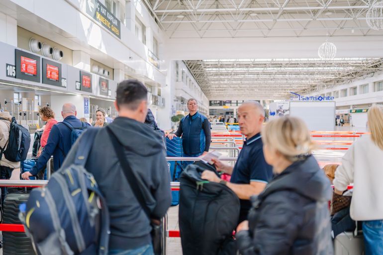 Antalya, Turkey - March 1, 2025 - Passengers waiting in line at an airport check-in counter with luggage. The airport has a modern design with a high ceiling and bright lighting.