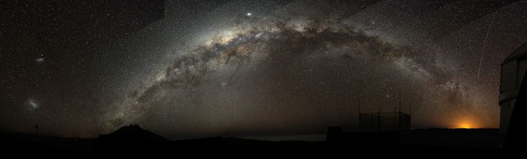 - Panorama - The Milky Way arch emerging from the Cerro Paranal on the left, and sinking into the Antofagasta's night lights. The bright object in the centre, above the Milky Way is Jupiter, somehow elongated due to the panoramic projection. The Magellanic Clouds are visible on the left side, and a plane has left a visible trace on the right, along the Vista enclosure - ArchBruno Gilli/ESO