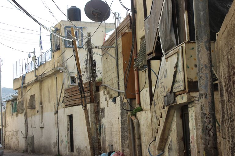 2-صورة لمنزل أم ناصر الرجبي والبؤرة الاستيطانية بجوارها وتظهر أيضا كاميرات المراقبة وعلم إسرائيل(الجزيرة نت)