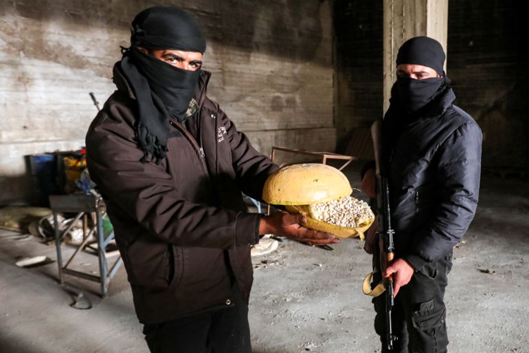A Syrian rebel fighter holds a container of pills of Captagon, a brand name of the drug psychostimulant Fenethylline, discovered at a drug manufacturing facility in the city of Douma in the Eastern Ghouta region on the eastern outskirts of Damascus on December 12, 2024. The dramatic collapse of Bashar al-Assad's Syrian regime has thrown light into many of the dark corners of his rule, including the industrial-scale export of the banned drug Captagon. Victorious Islamist fighters have seized military bases and distribution hubs for the amphetamine-laced stimulant, which has flooded the black market across the Middle East. (Photo by Bakr ALKASEM / AFP)