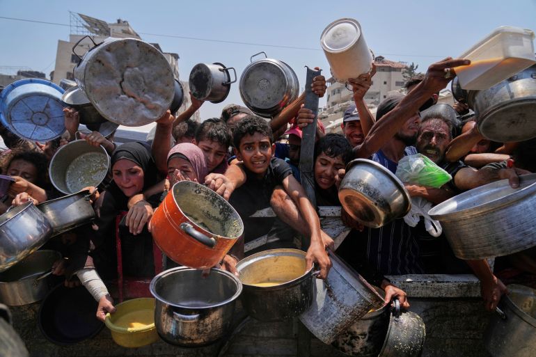 Palestinians struggle to get donated food at a community kitchen in Gaza City, northern Gaza Strip, July 26, 2025. (AP Photo/Abdel Kareem Hana)