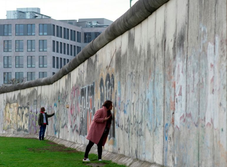 People touch remains of the Berlin Wall at the Wall memorial on Bernauer Strasse in Berlin, Germany, November 8, 2019. On November 9th Germany will mark the 30th anniversary of the fall of the Berlin Wall (Berliner Mauer) in 1989. REUTERS/Fabrizio Bensch