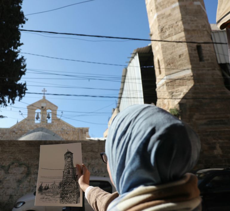 الفنانة ولاء شبلاق أثناء توثيق معلم أثري في البلدة القديمة بغزة، ضمن مشروعها "مسار ما تبقى لنا"