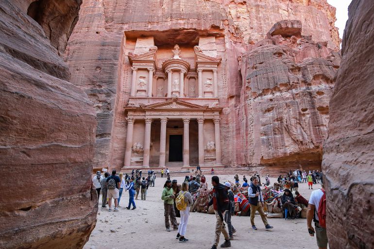 Visitors tour near the Treasury at the ruins of the ancient Nabatean city of Petra in southern Jordan on December 12, 2022. After years in which the Covid pandemic turned the storied "Rose City" into a ghost town, Jordan tourism authorities confirm that Petra, famous for its stunning temples hewn out of the rose-pink cliff faces, is back in business and drew 900,000 visitors last year, close to the previous record of one million set in 2019. (Photo by Khalil MAZRAAWI / AFP)