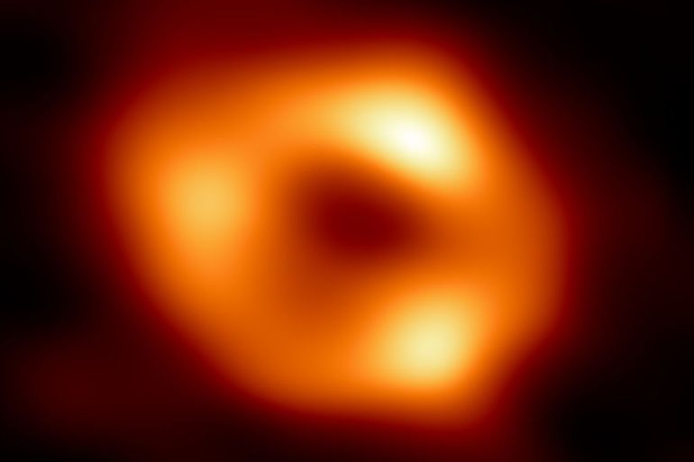 This is the first image of Sgr A*, the supermassive black hole at the centre of our galaxy. It’s the first direct visual evidence of the presence of this black hole. It was captured by the Event Horizon Telescope (EHT), an array which linked together eight existing radio observatories across the planet to form a single “Earth-sized” virtual telescope. The telescope is named after the event horizon, the boundary of the black hole beyond which no light can escape.   Although we cannot see the event horizon itself, because it cannot emit light, glowing gas orbiting around the black hole reveals a telltale signature: a dark central region (called a shadow) surrounded by a bright ring-like structure. The new view captures light bent by the powerful gravity of the black hole, which is four million times more massive than our Sun. The image of the Sgr A* black hole is an average of the different images the EHT Collaboration has extracted from its 2017 observations.  In addition to other facilities, the EHT network of radio observatories that made this image possible includes the Atacama Large Millimeter/submillimeter Array (ALMA) and the Atacama Pathfinder EXperiment (APEX) in the Atacama Desert in Chile, co-owned and co-operated by ESO is a partner on behalf of its member states in Europe.