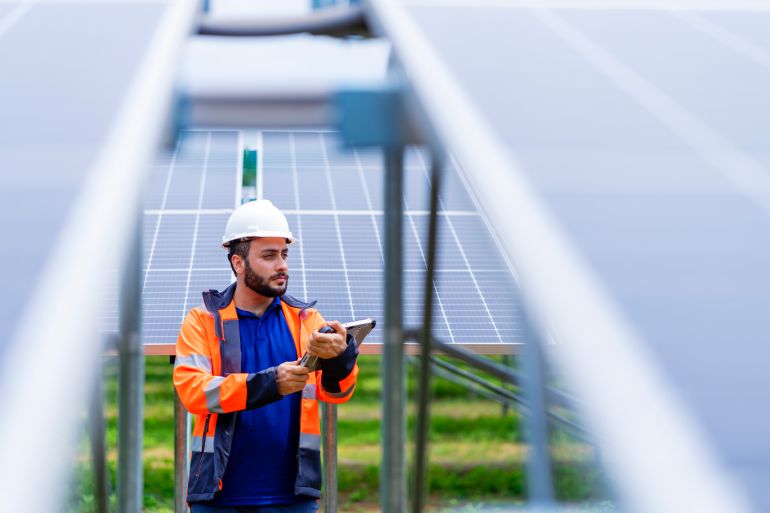 Engineer working at Solar Farm using tablet computer verify completeness of installation work. Professional engineering for solar energy design and installation services. Sustainable Energy and Environment friendly. Alternative green energy concept.
