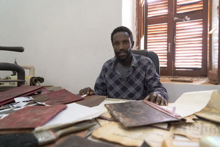 Bule sits at the museum workshop where he restores and binds manuscripts [Jaclynn Ashly/Al Jazeera]