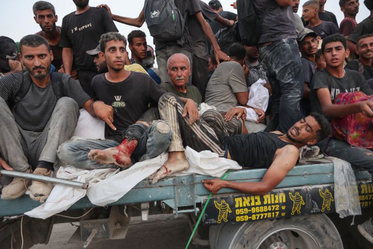 Palestinians transport an injured man as bring back aid parcels they managed to procure west of Beit Lahia on July 29, 2025, after aid trucks entered the Israel-besieged Gaza Strip from the northern Zikim border crossing. (Photo by Omar AL-QATTAA / AFP)