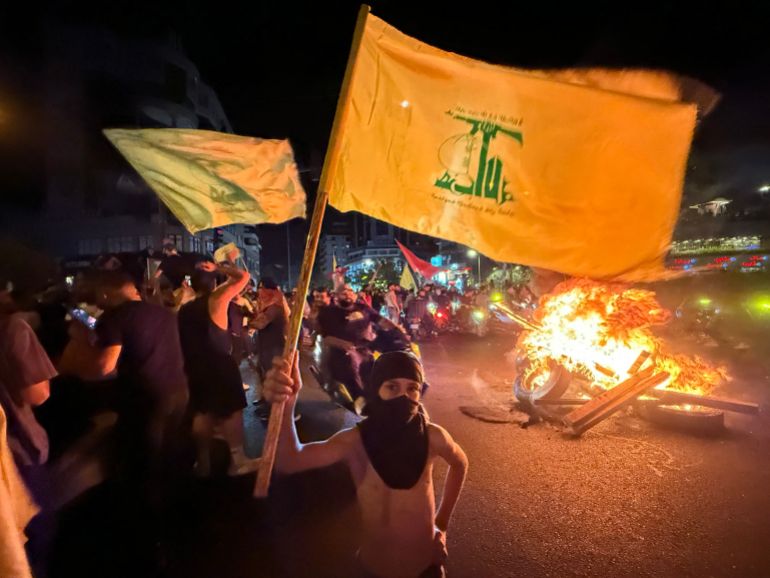 Supporters of Lebanon's Hezbollah militant group block the streets with burning tires as they rally in cars and motorbikes to protest the government's endorsement of a plan to disarm it, in Beirut's southern suburbs early on August 8, 2025.