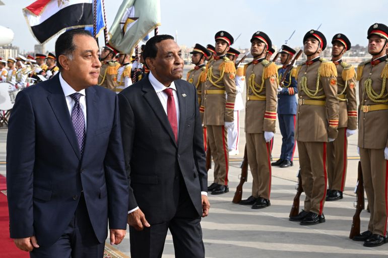Egypt's Prime Minister Mostafa Madbouly (L) welcomes his counterpart from Sudan Kamil Idris upon his arrival at the Cairo International airport in Egypt's capital on August 7, 2025.