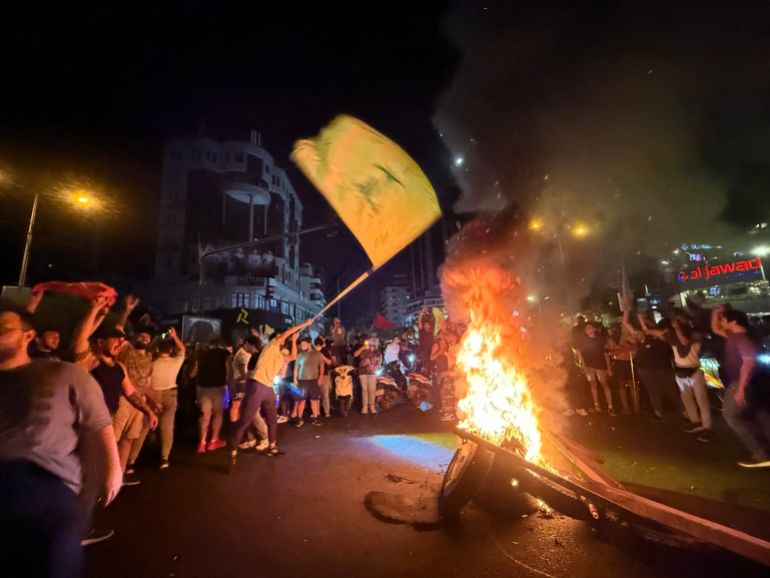 Supporters of Lebanon's Hezbollah militant group block the streets with burning tires as they rally in cars and motorbikes to protest the government's endorsement of a plan to disarm it, in Beirut's southern suburbs early on August 8, 2025.