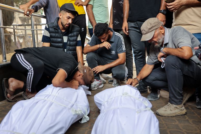 Palestinians mourn over the shrouded bodies of loved ones killed the previous day while seeking aid near Zikim, west of Beit Lahia, in the northern Gaza Strip, at Al-Shifa hospital in Gaza City on August 10, 2025.
