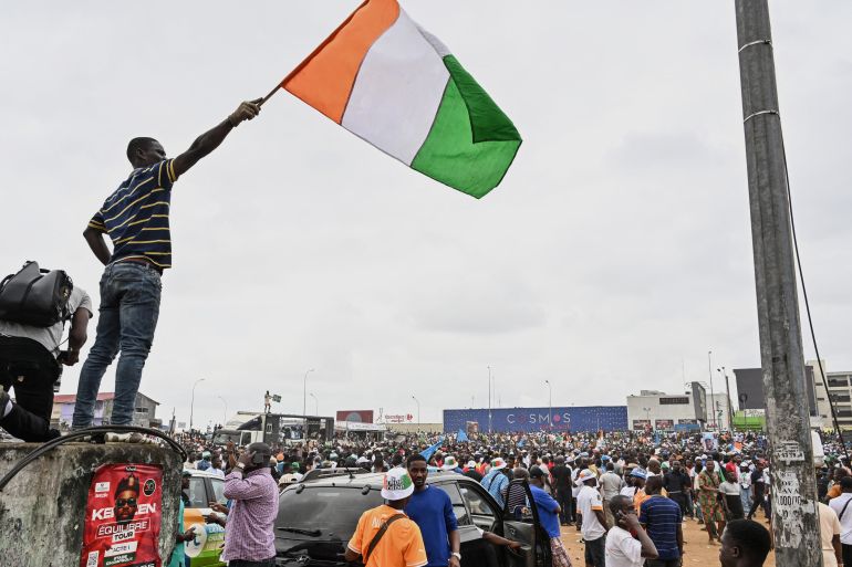 An opposition supporter waves a flag from Ivory Coast during a march calling for an inclusive election in the neighborhood of Yopougon in Abidjan on August 9, 2025, ahead of the presidential election on October 25, 2025.
