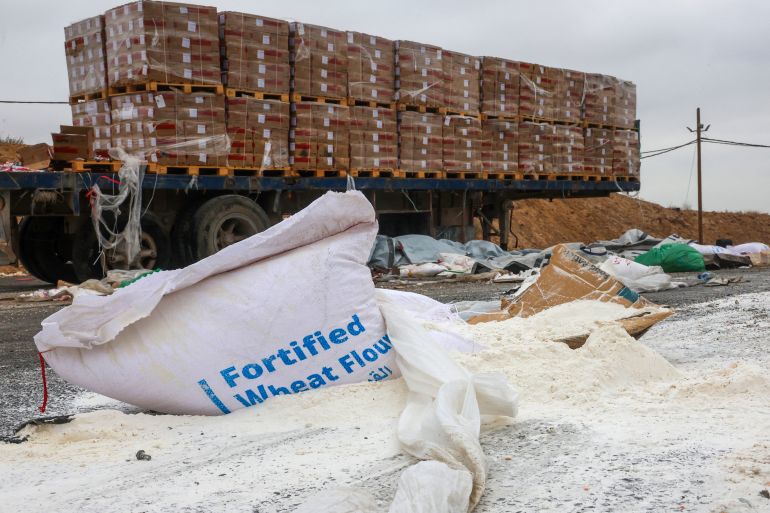 Damaged humanitarian aid for Palestinians in Gaza lies scattered on the ground next to broken-down trucks near the border with the Gaza Strip, close to the Kissufim crossing in southern Israel, on August 13, 2025, amid the ongoing war with the Palestinian militant movement Hamas. (Photo by Jack GUEZ / AFP)
