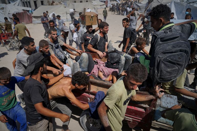 Palestinians are carried after being wounded while trying to reach trucks carrying humanitarian aid en route to Gaza City, in the outskirts of Beit Lahiya, northern Gaza Strip, Friday, Aug. 1, 2025. (AP Photo/Jehad Alshrafi)