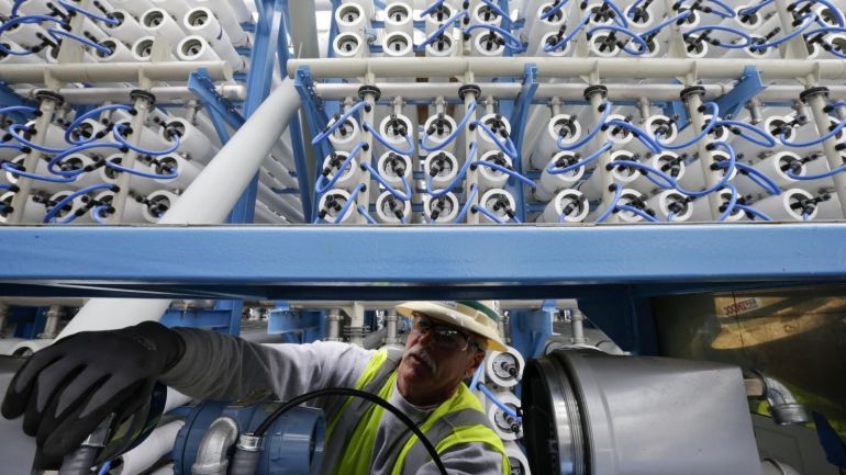 In this March 11, 2015 picture, a worker adjusts equipment among some of the 2000 pressure vessels that will be used to convert seawater into fresh water through reverse osmosis in the western hemisphere's largest desalination plant Wednesday, March 11, 2015, in Carlsbad, Calif. Despite the San Diego region's costly investments to prepare for drought, the measures count for nothing under sweeping statewide cuts to urban water use approved this month. (AP Photo/Gregory Bull)