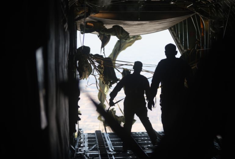 GAZA - AUGUST 6: Jordanian air force personnel in a Jordanian C-130 military aircraft perform an air drop of aid and humanitarian supplies on August 6, 2025 in Gaza. On Wednesday, the Royal Jordanian Air Force carried out air drops of food and other aid over Gaza, alongside aircraft from other nations carrying 54 tons of humanitarian supplies. Airdrops of aid have resumed in recent weeks in an attempt to alleviate the severe lack of food and other essentials reaching people in Gaza, where the World Food Programme (WFP) has said over half a million people are enduring famine-like conditions, as Israel continues to restrict the flow of aid. (Photo by Salah Malkawi/Getty Images)