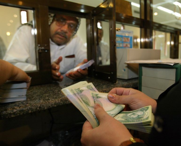 BAGHDAD, IRAQ -OCTOBER 15: An Iraqi bankteller counts the new Iraqi dinar while dealing with a customer at the Bank of Baghdad October 15,2003 in Baghdad as the currency is introduced into circulation for the first time, missing on the bills is the smiling face of Saddam Hussein. Unlike the old ones, the new notes are nearly impossible to forge. Its is a major hope that the new currency will be a giant step towards securing the economic future of the country. (Photo by Paula Bronstein/Getty Images)