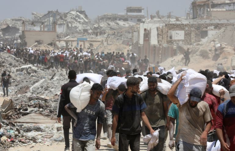 Palestinians carry aid supplies that entered Gaza through Israel, in Beit Lahia in the northern Gaza Strip, August 1, 2025. REUTERS/Dawoud Abu Alkas