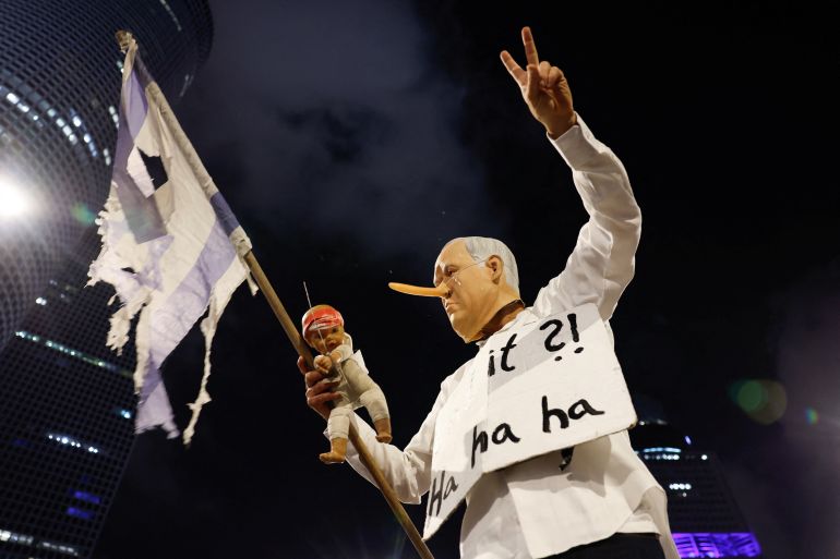 A demonstrator wearing a mask depicting Israeli Prime Minister Benjamin Netanyahu gestures, during a protest to demand the immediate release of hostages held in Gaza since the October 7, 2023, attack on Israel by Hamas and to end the war, in Tel Aviv, Israel, August 2, 2025. REUTERS/Ammar Awad