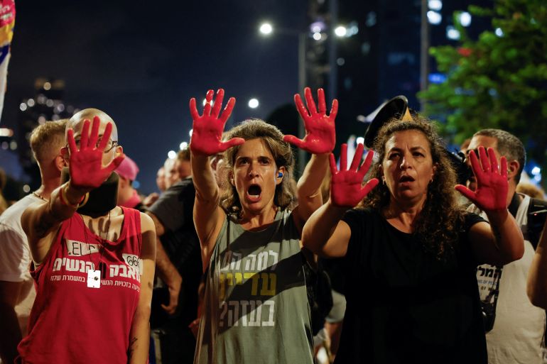 متظاهرون يرفعون أيديهم المصبوغة بالأحمر في تل أبيب في مشهد رمزي يعكس غضبهم من استمرار الحرب وسقوط ضحايا واختيار الطلاء الأحمر ليحاكي الدم في رسالة احتجاجية ضد ما يرونه استنزافا بلا نهاية (رويترز)