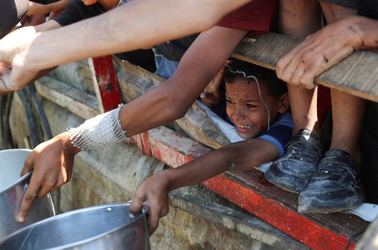 A Palestinian child waits to receive food from a charity kitchen, amid a hunger crisis, in Gaza City, August 2, 2025. REUTERS/Mahmoud Issa TPX IMAGES OF THE DAY