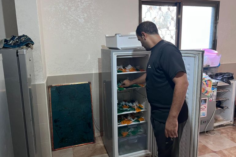 المجدلاوي أثناء عمله في تعبئة ثلاجته بأكياس البراد لتبريدها (الجزيرة)