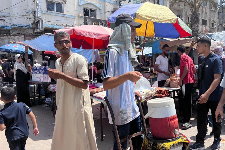 شاب يبيع المياه المثلجة للمواطنين في سوق النصيرات (الجزيرة)