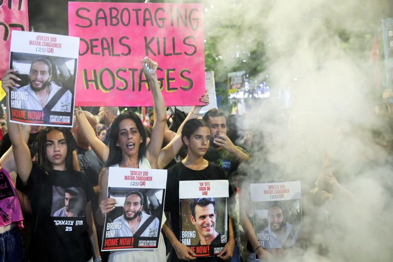 Einav Zangauker (2nd-L), mother of kidnapped Israeli Matan Zangauker, holds a sign depicting him during a demonstration organised by the families of the Israeli hostages taken captive in the Gaza Strip since the October 2023 calling for action to secure their release and a ceasefire in the war against Hamas, outside the Defence Ministry headquarters in Tel Aviv, on August 23, 2025.