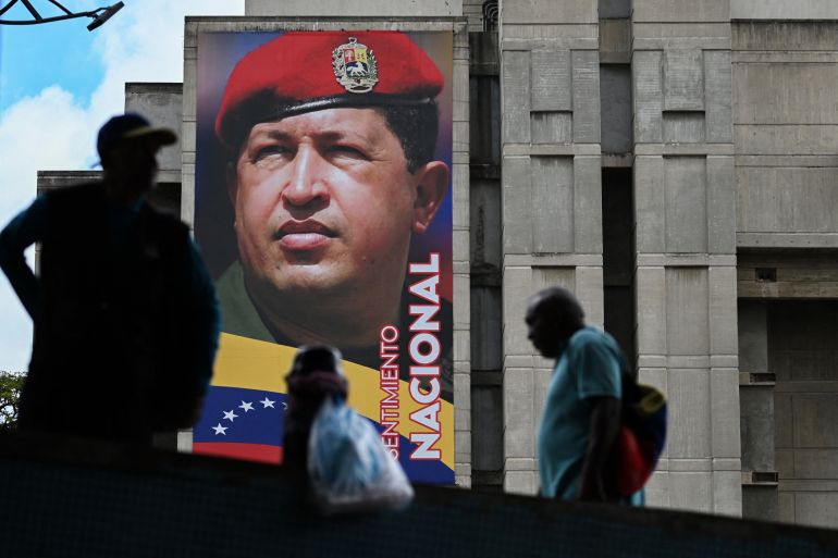 People walk past a mural of Venezuela's former President Hugo Chavez in Caracas on September 5, 2025. (Photo by Juan BARRETO / AFP)