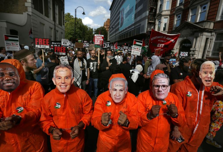 LONDON, ENGLAND - SEPTEMBER 06: Protesters wear masks depicting world leaders in orange jumpsuits during the march on September 6, 2025 in London, England. The National March for Palestine 'Stop Starving Gaza' is the 30th march since the war began in October 2023 and comes ahead of Israel's president Herzog visit to the UK next week. (Photo by Martin Pope/Getty Images)