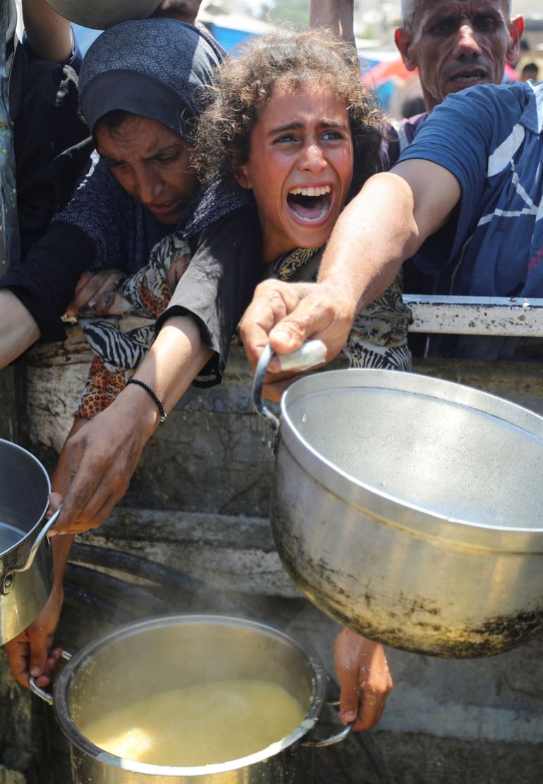 Palestinians react as they wait to receive food from a charity kitchen, amid a hunger crisis, in Gaza City, August 2, 2025. REUTERS/Mahmoud Issa